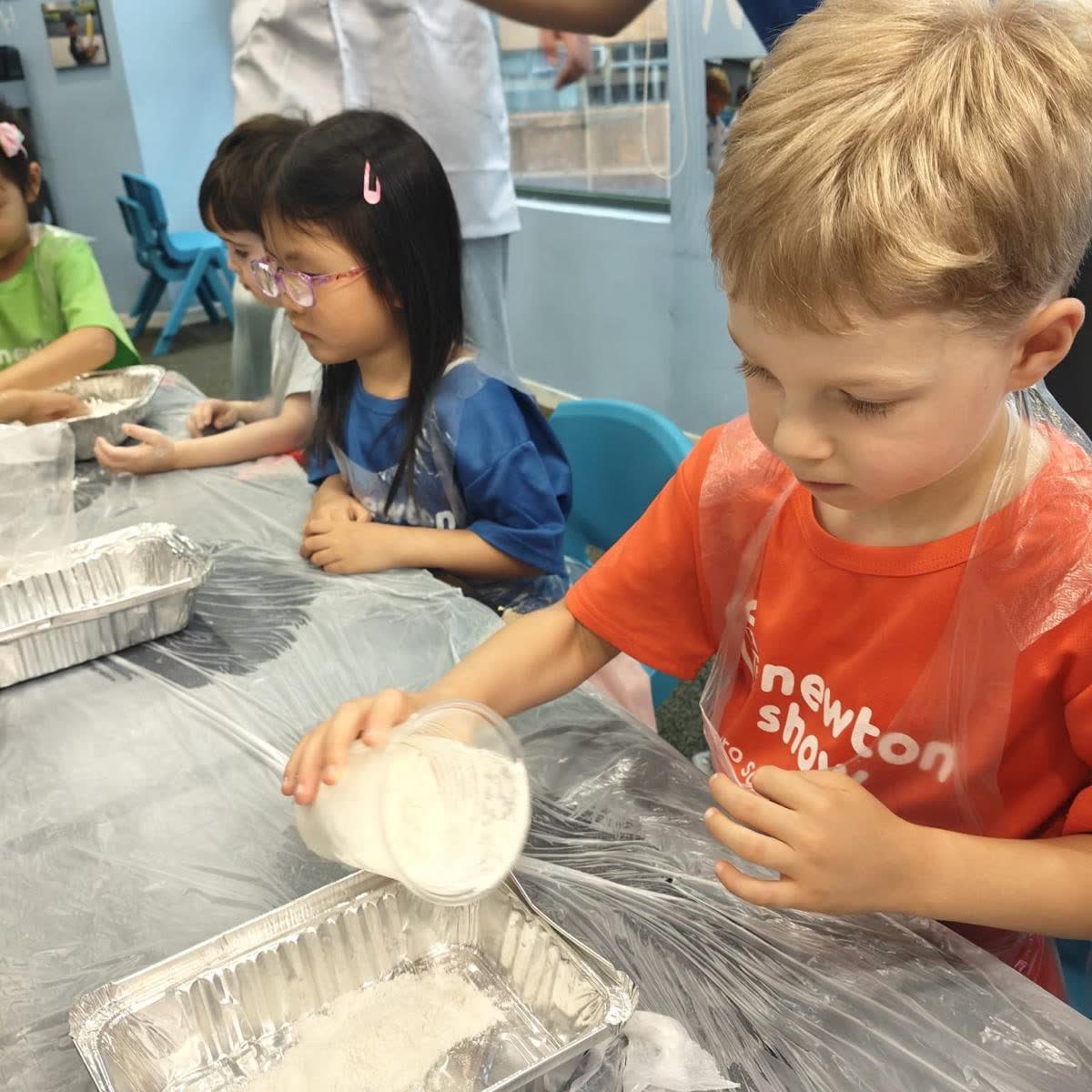 Children working through hands-on science trays together at a Newtonshow Hong Kong holiday camp