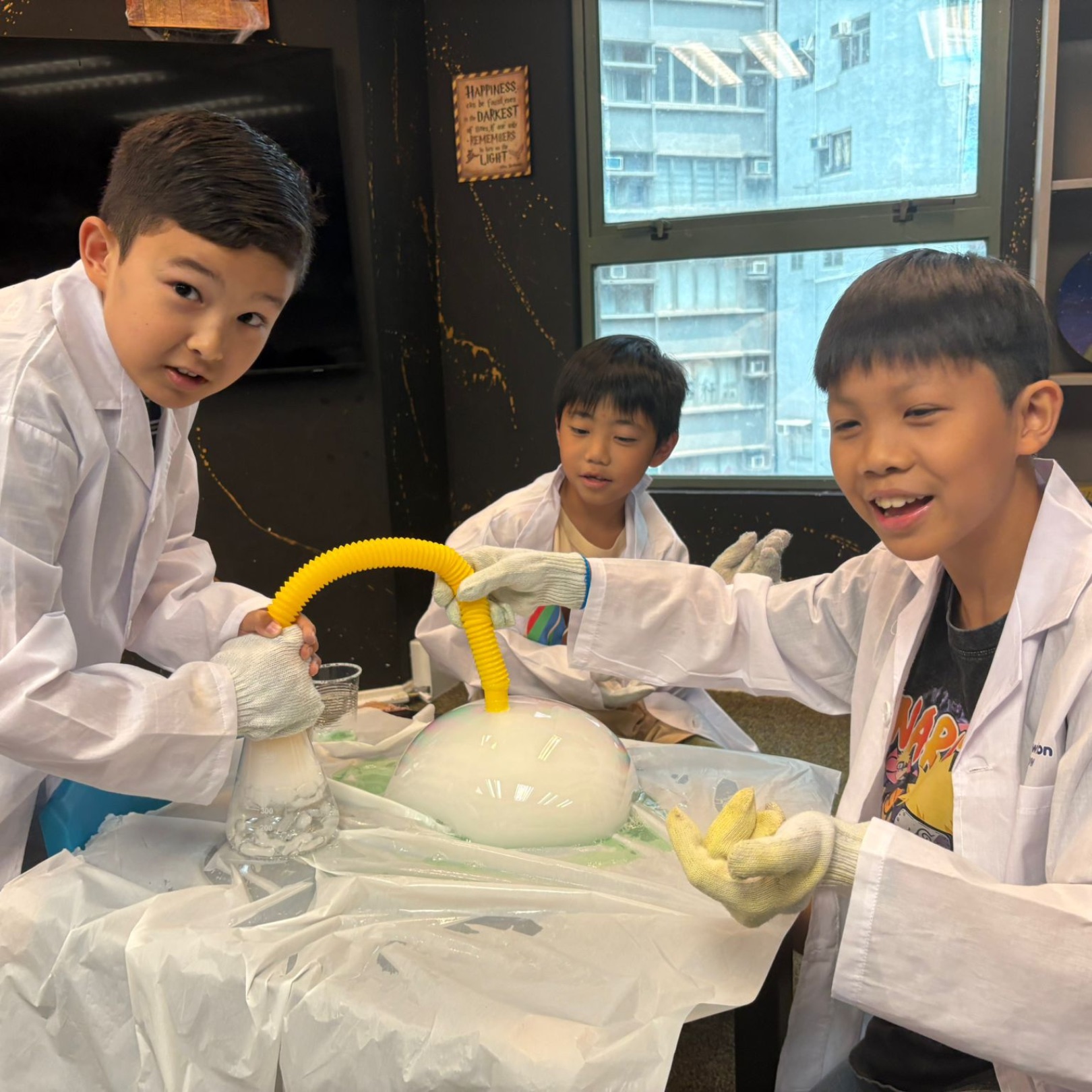 Boys in lab coats stretching a giant dry-ice bubble at a Newtonshow Hong Kong winter camp