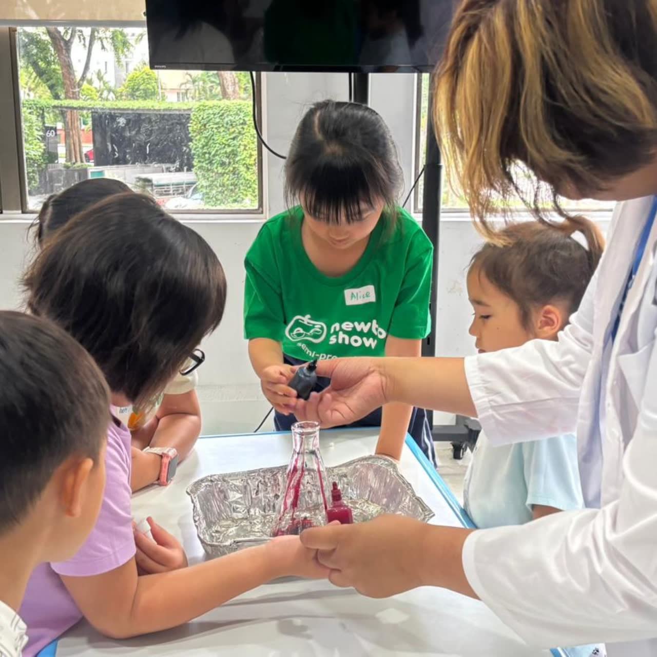 Children investigating a bright chemical reaction with a Newtonshow teacher at a Hong Kong science camp