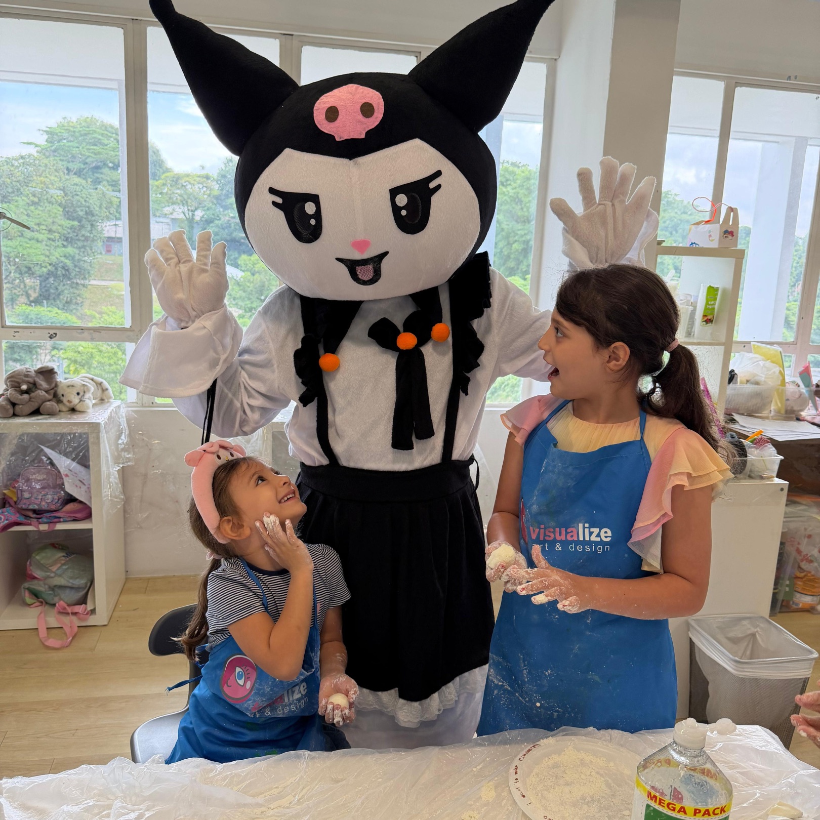 Two girls baking with a kawaii costumed character at a Newtonshow Hong Kong winter camp